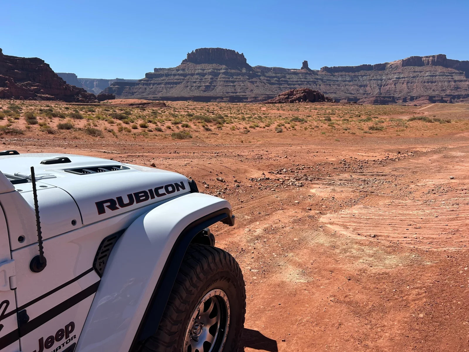 White Jeep overlooking a broad red rock valley