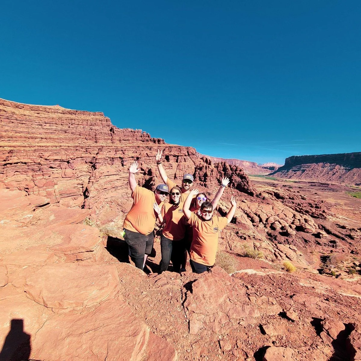 Travelers standing at a broad red rock canyon overlook