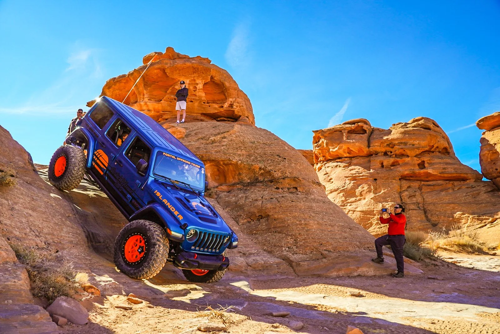 Blue Jeep climbing a steep sandstone ledge