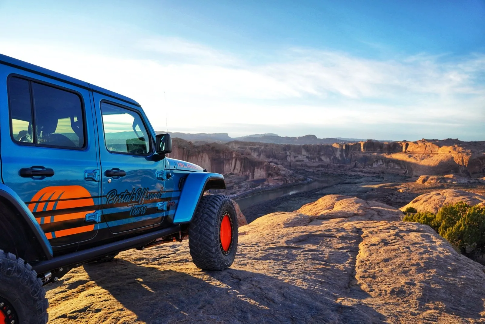 Jeep parked beside rolling slickrock at sunset