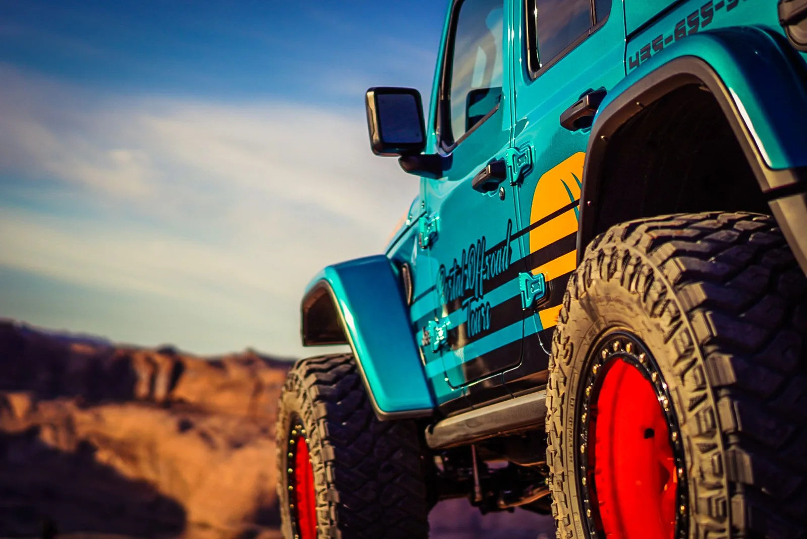 Close view of an off-road Jeep and tire against the sky