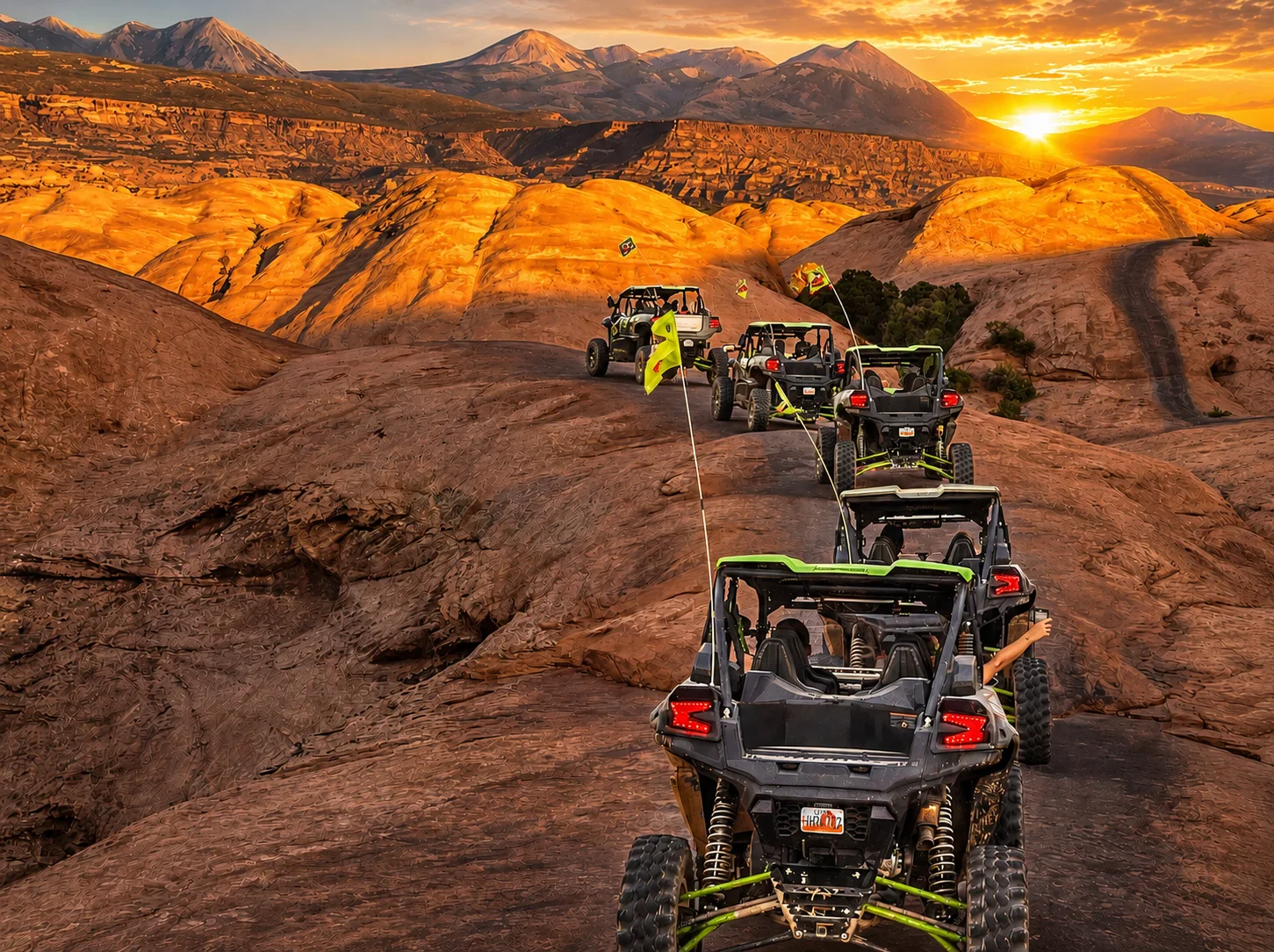 Line of green UTVs beneath sunlit sandstone ridges