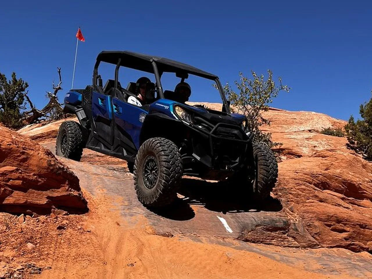 Blue UTV climbing a sandstone ledge on Hell’s Revenge